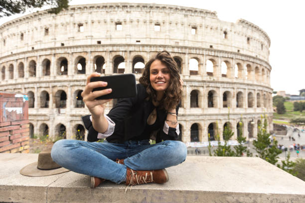 sourire de femme assise jambes traversé prenant selfie - international landmark italy amphitheater ancient photos et images de collection