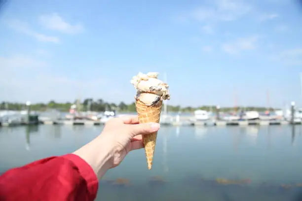 A woman holds ice cream in her hand in a waffle cone