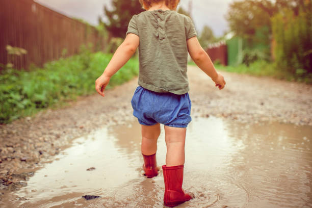 istock Little boy playing in puddle, rear view 1024629910