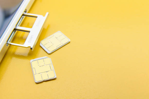 Broadband 5G mobile communication technology concept : SIM card tray / dual SIM card slot with two nano SIM cards on yellow background. SIM stores international mobile subscriber identity IMSI number. concepto de tecnología de comunicación móvil de 5g banda ancha: bandeja de tarjeta sim / ranura para tarjeta sim dual con dos nano sim tarjetas sobre fondo amarillo. sim almacena la identidad internacional de suscriptor móvil número imsi.