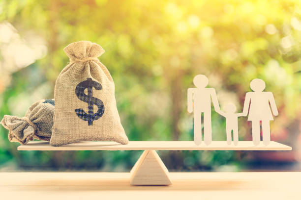 Money saving for kids, family financial wealth management concept : Dollar or cash in hemp bags or burlap sacks and a white paper cut (dad, mom and son) on wood balance scale. Green nature background. dinero ahorro para niños, concepto de gestión del patrimonio financiero familiar: dólares o efectivo en bolsas de cáñamo o sacos de arpillera y un libro blanco corte (papá, mamá e hijo) en la escala de equilibrio de madera. fondo de naturaleza verde