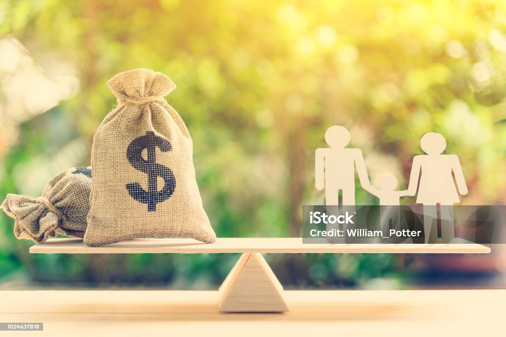 Money saving for kids, family financial wealth management concept : Dollar or cash in hemp bags or burlap sacks and a white paper cut (dad, mom and son) on wood balance scale. Green nature background. Family Stock Photo