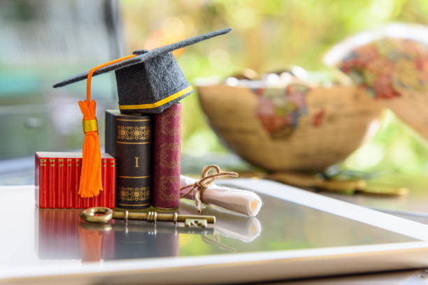 istock Graduate study abroad program for opening or expand world view concept : Graduation cap or hat, a key, world globe map, foreign text book on laptop, depicts achievement or success in online education 1024637986