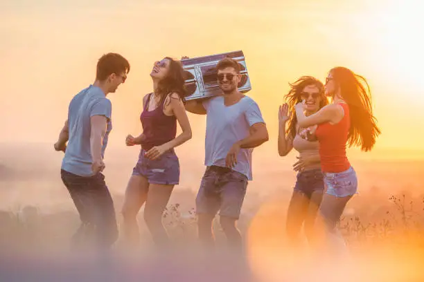 Photo of The young people dancing with a boom box on the sunny background