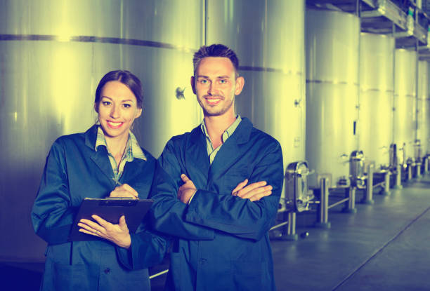 istock Portrait of two experts standing with clipboard in wine processing section 1024652684