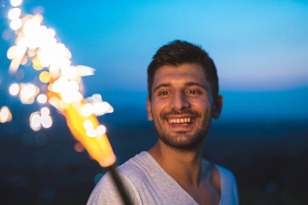 The happy man stand with a firework stick. evening night time
