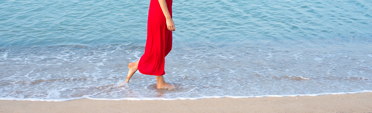Woman walking barefoot on the beach in summer.