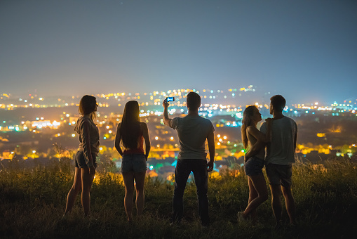 The five people make a selfie on a background of the city. evening night time