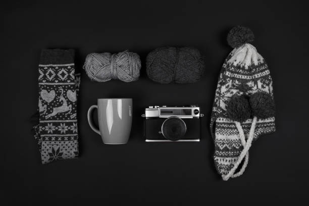 Invierno sombrero y calcetines, hilados de lana, taza y analógico cámara sobre fondo negro - foto de stock