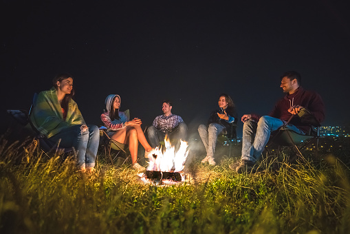 The five people rest near the bonfire. evening night time