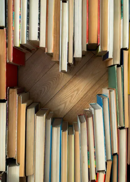 Photo of Love concept of heart shape from old vintage books on wooden floor background. Vintage color tone style composition of love with open book heart shape