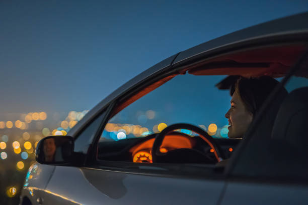 la atractiva mujer se sienta en el coche en el fondo de la ciudad. noche - car driving dashboard night fotografías e imágenes de stock