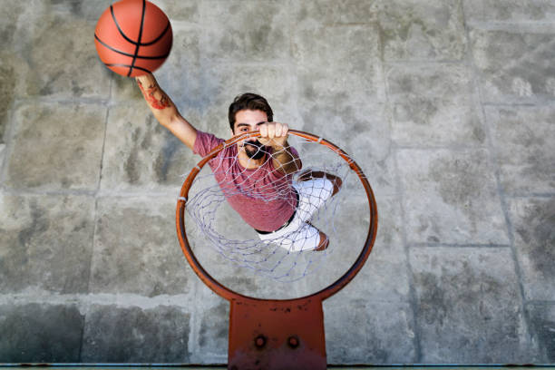 giovane giocatore hipster che schiacca il basket nel cerchio - basketball slam dunk basketball hoop sport foto e immagini stock