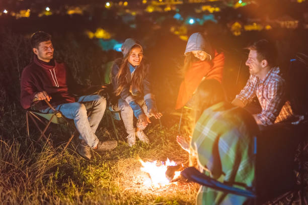 The five friends warming hands above the bonfire. evening night time