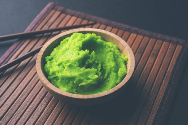 istock Green wasabi sauce or paste in bowl, with chopsticks or spoon over plain colourful background. selective focus 1024674806