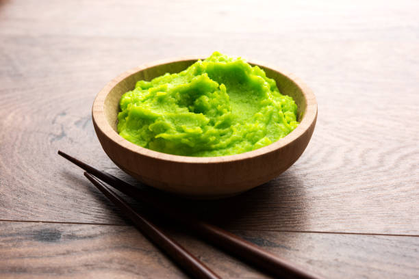 istock Green wasabi sauce or paste in bowl, with chopsticks or spoon over plain colourful background. selective focus 1024675366