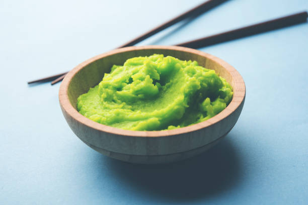 istock Green wasabi sauce or paste in bowl, with chopsticks or spoon over plain colourful background. selective focus 1024677096