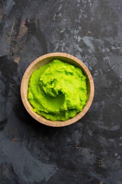 istock Green wasabi sauce or paste in bowl, with chopsticks or spoon over plain colourful background. selective focus 1024677406