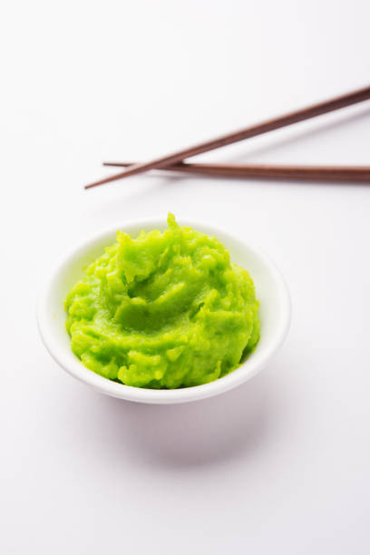 istock Green wasabi sauce or paste in bowl, with chopsticks or spoon over plain colourful background. selective focus 1024677776