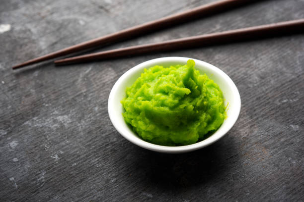 istock Green wasabi sauce or paste in bowl, with chopsticks or spoon over plain colourful background. selective focus 1024678208