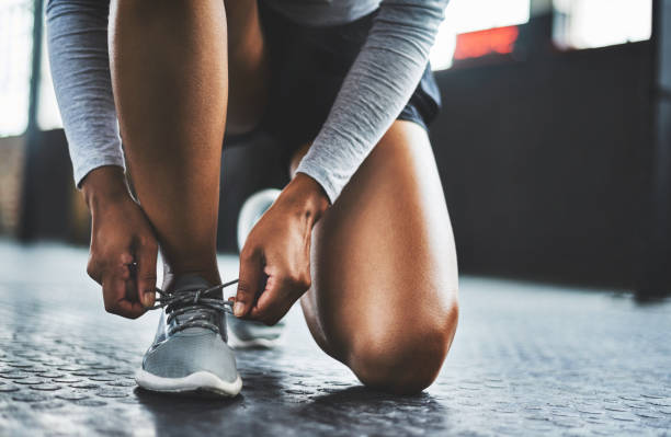 Get laced up and get going Cropped shot of a woman tying her shoelaces in a gym sports shoe photos stock pictures, royalty-free photos & images