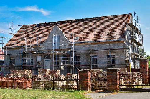 Restoration of an old farmhouse. In the garden are new roof tiles for the repair of the roof and the old bricks of the facade.