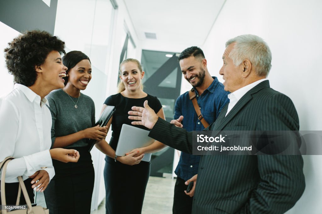 Corporate professional having informal meeting Business people standing together in office having casual discussion. Corporate professional having informal meeting in office corridor. Networking Stock Photo