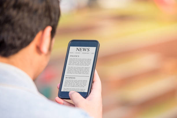 istock News article concept on phone screen. Man holding smartphone reading news article on screen. 1024712374