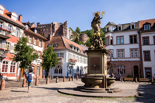Heidelberg, Germany. The Madonna statue in Kornmarkt square at daylight, with Heidelberg Castle (Heidelberger Schloss) in the background