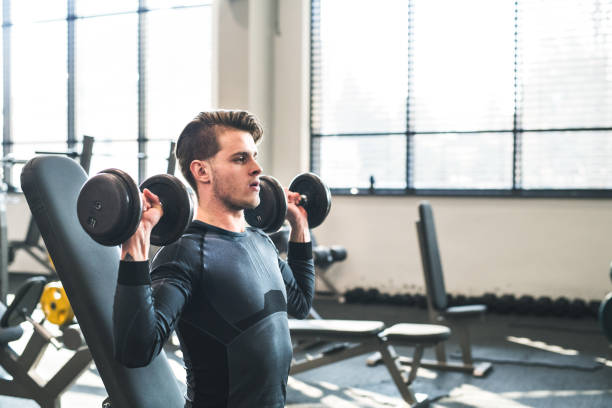 istock Young fit man in gym exercising with dumbbells. Copy space. 1024775126