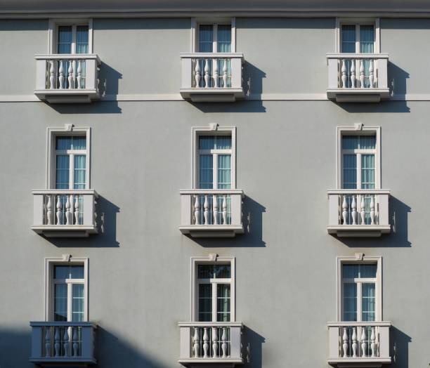 Elegant light grey facade with large windows and small white balconies with columns, in classical style