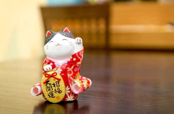 istock Selective focus Maneki Neko, Japanese lucky cat, on a Wooden table with blurred background and copy space for text input. 1024793368