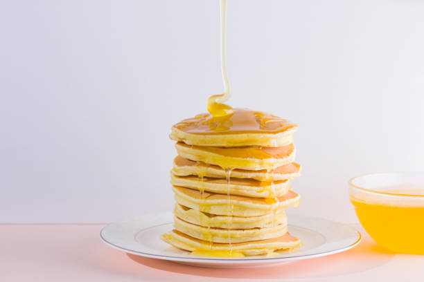 istock Pancakes on a white pink background. Hot pancakes with honey on a white plate with copy space. Delicious dish for breakfast. Honey flows down from a wooden stick on a dish 1024805408