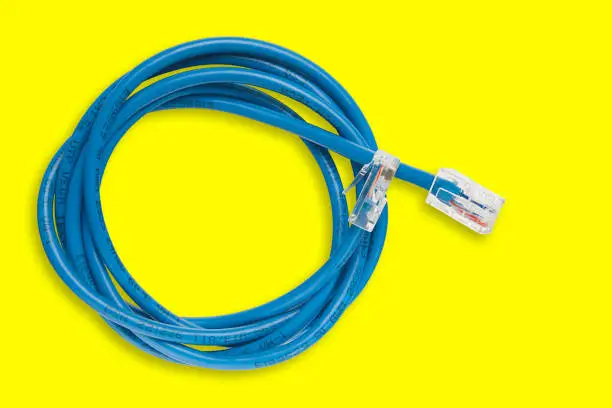 Photo of Twisted pair (patch cord) blue network Internet cable on a yellow background. Top view.