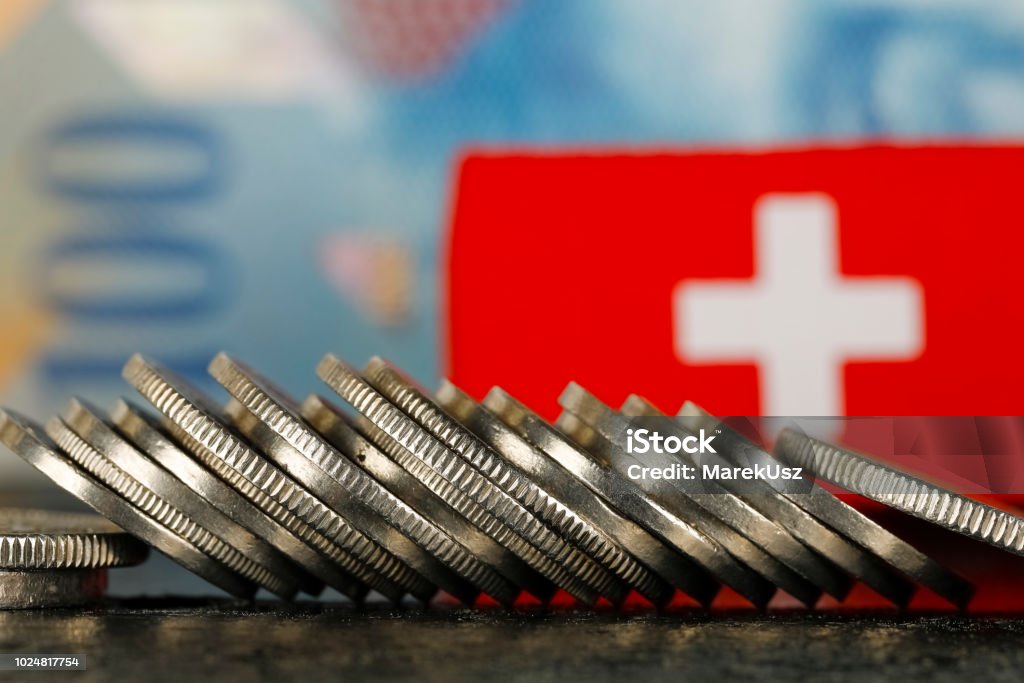 Swiss Money and Flag There are various Swiss coins visible against background of one hundred francs banknote and there is Swiss flag as well Switzerland Stock Photo