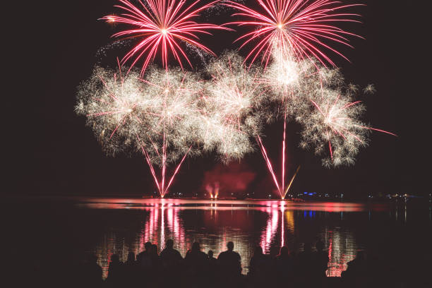 istock Beautiful and colorful fireworks display with unrecognizable crowd people watching at river's edge in France 1024830330