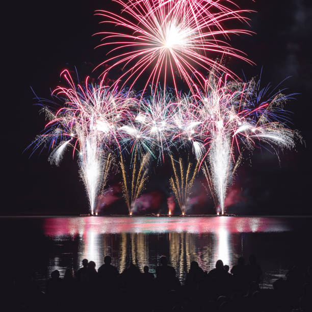 istock Beautiful and colorful fireworks display with unrecognizable crowd people watching at river's edge in France 1024834356