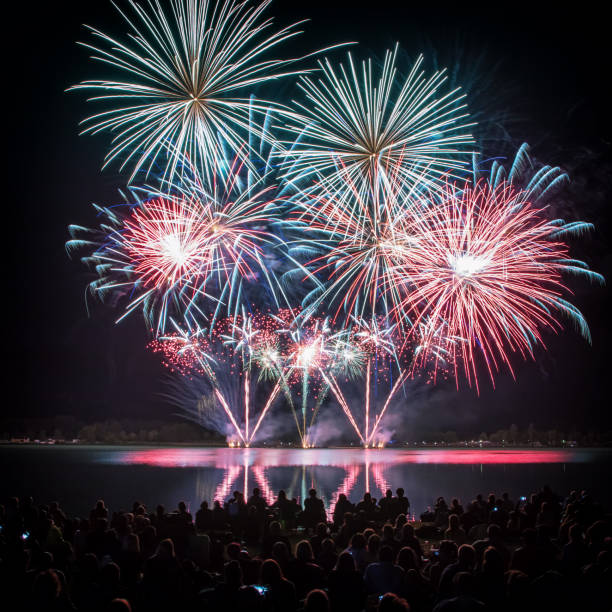 istock Beautiful and colorful fireworks display with unrecognizable crowd people watching at river's edge in France 1024834504