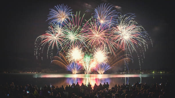 istock Beautiful and colorful fireworks display with unrecognizable crowd people watching at river's edge in France 1024835272