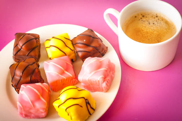 varias tortas pequeñas con formación de hielo en un plato blanco con un café - fondant fancies fotografías e imágenes de stock