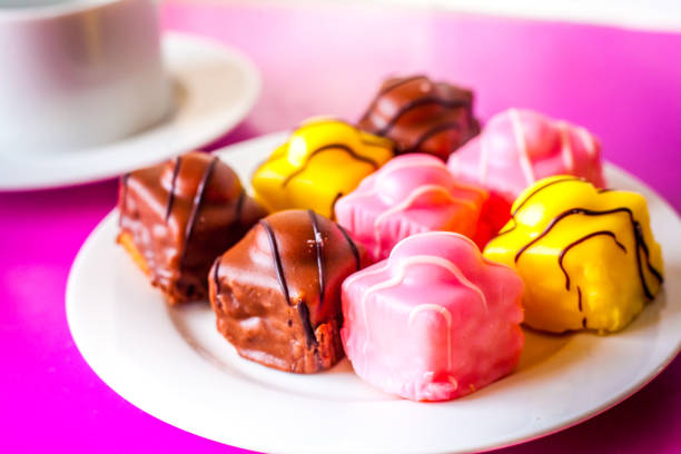 varias tortas pequeñas con formación de hielo en un plato blanco con un café - fondant fancies fotografías e imágenes de stock