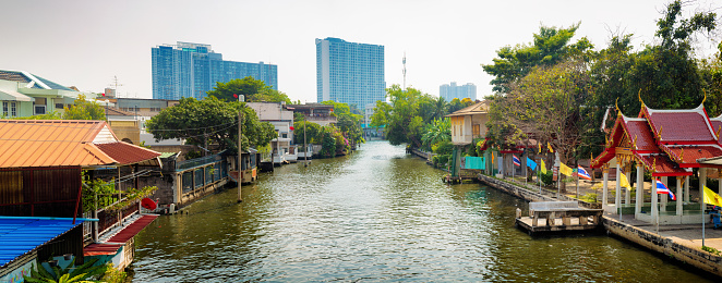 Bangkok Khlong Dan River panorama with apartment buildings and small houses on a Sunny Winter day.