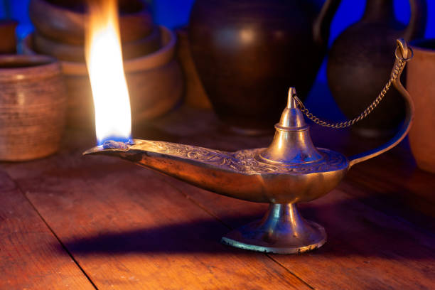 istock Ancient oil lamp burns on a wooden table 1024893374