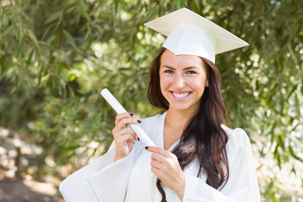 Attractive Mixed Race Girl Celebrating Graduation Outside In Cap and Gown with Diploma in Hand Attractive Mixed Race Girl Celebrating Graduation Outside In Cap and Gown with Diploma in Hand. mortarboard photos stock pictures, royalty-free photos & images