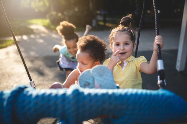 istock Smiling sisters playing on a swing at a local playground 1024941846