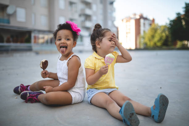 Messy children enjoying melting ice cream in summer Cute and lovely mixed race siblings enjoying their time together in a city public park, eating ice cream. melting brain stock pictures, royalty-free photos & images
