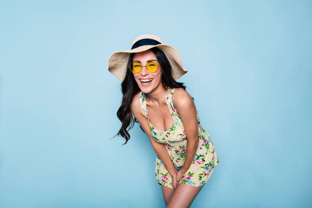 Crazy funny mood. Happy cute summer brunette woman in hat, sunglasses and colorful dress, stylish girl have a fun and posing on blue background Beautiful stylish and elegance brunette woman in summer hat and dress while dancing and posing over blue background sundress stock pictures, royalty-free photos & images