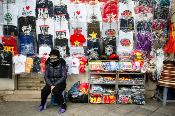 January 27, 2018 - Hanoi, Vietnam: A Vietnamese woman at her market stall that sells t-shirt souvenirs in the Old Quarter of the city in Hanoi, Vietnam.