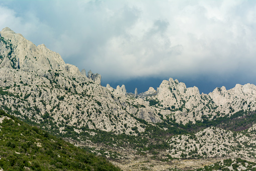 Cliffs on top of the Velebit Mountain in Croatia in Tulove Grede Area with upcoming storm and cloudy sky. This mountain hills are above tunnel and highway to Adriatic seaside.