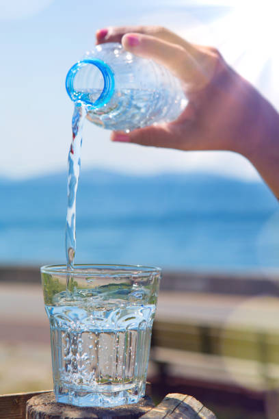 istock The hand is pouring water from the bottle on the beach. 1025001534